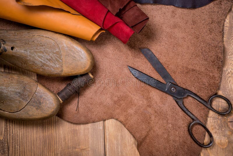 Insieme degli strumenti di cuoio del mestiere su fondo di legno Posto di lavoro per il calzolaio