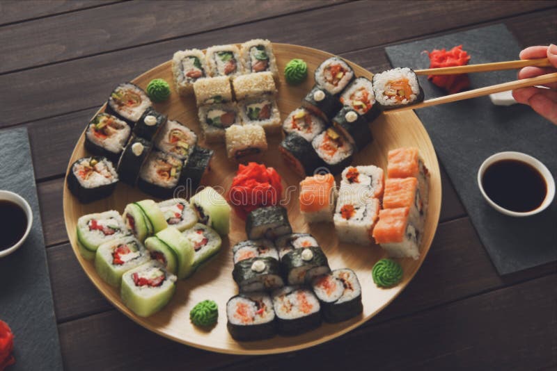 Insieme del maki e dei rotoli dei sushi a legno rustico nero immagine stock libera da diritti Insieme del maki e dei rotoli dei sushi a legno rustico nero immagine stock libera da diritti