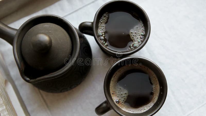 Insieme di caffè dell'argilla Cezve e due tazze con la cottura a vapore del coffe