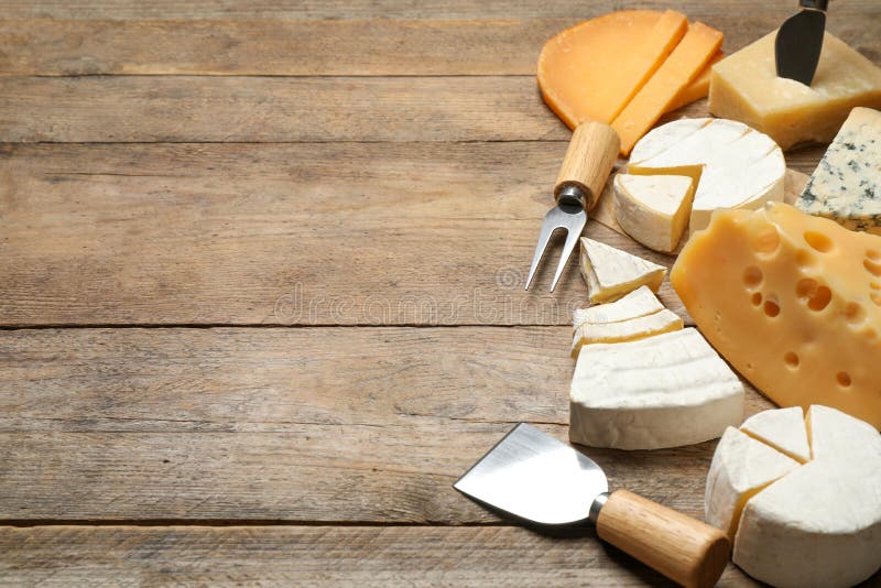 Insieme di formaggi diversi e di coltelli e forchette speciali su tavola di legno Spazio per il testo fotografia stock libera da diritti