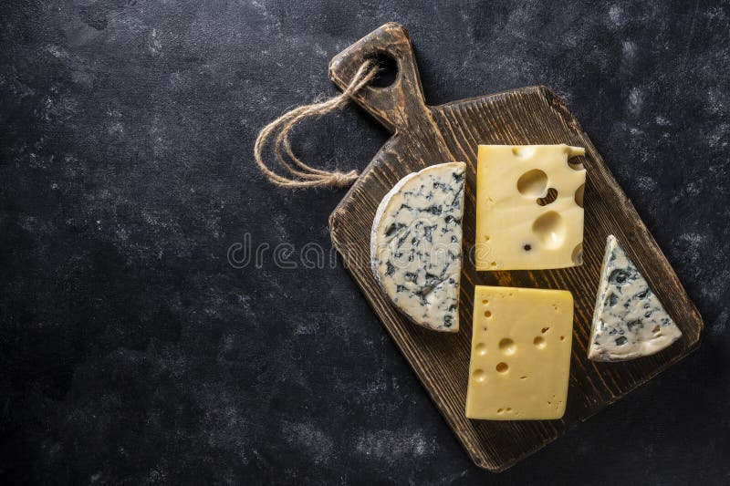 Insieme di formaggi diversi su tavolette di legno su uno spazio di chiusura in alto di fondo nero. Vari tipi di formaggio immagine stock