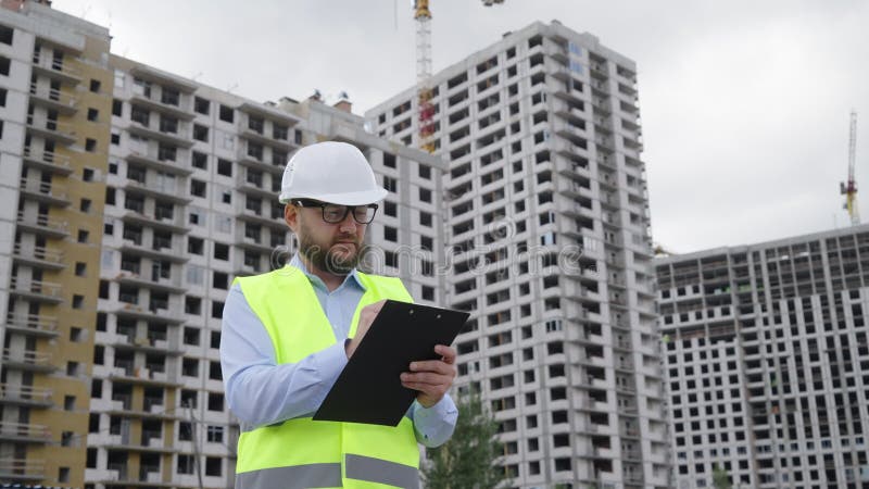 Inspector de construcción barbudo haciendo notas en el sitio de construcción