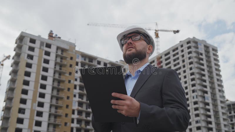 Inspector de construcción barbudo haciendo notas en el sitio de construcción