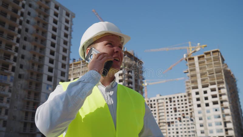 Inspector de edificios hablando por teléfono en el lugar de la construcción