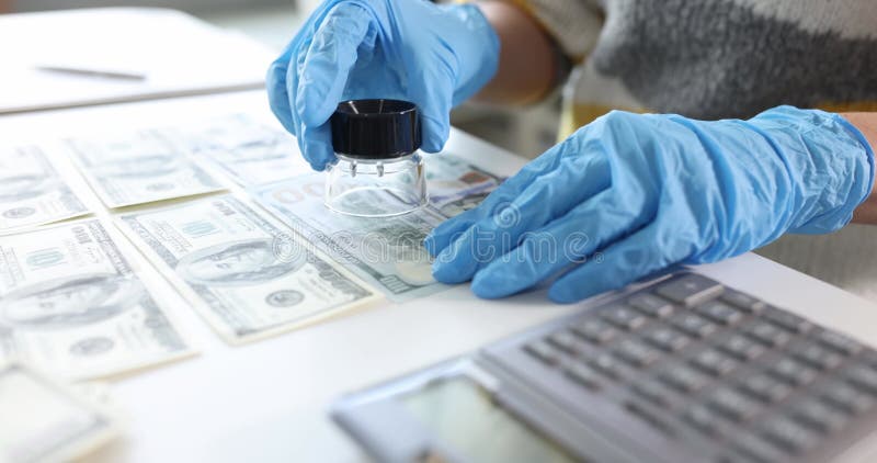 Inspector en guantes de goma mirando billetes de dólar usando vidrio de aumento a cámara lenta película de 4k