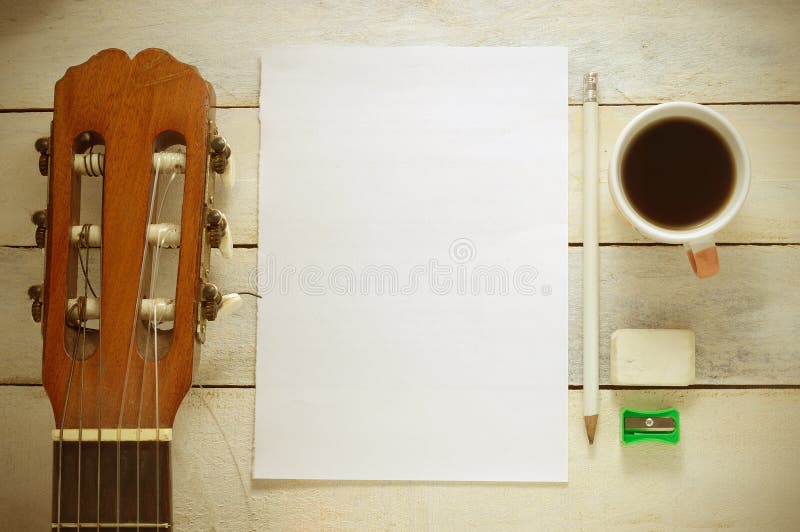 Inspirational background with a Spanish classical guitar on a wooden table while composing. Score sheet, a pencil and a cup of coffee for the music composer,. Abstract classical stock images, royalty-free photos and pictures