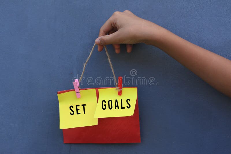 Inspirational quote - Set goals. With young girl holding origami paper notes hanging on wall. Motivational business typography. stock photography Inspirational quote - Set goals. With young girl holding origami paper notes hanging on wall. Motivational business typography. stock photography