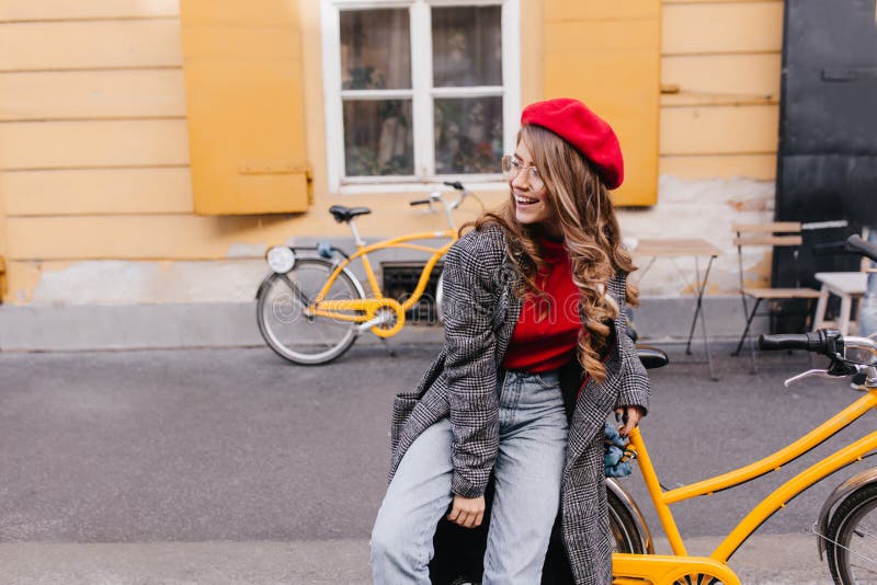 Inspired girl in blue jeans posing on the street and looking around with sincere laugh. Tired smiling woman in beret