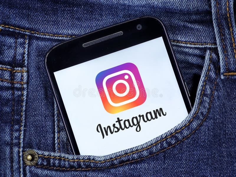 Instagram logo on cell phone screen in jeans pocket.