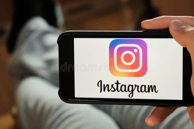 Instagram logo on the screen of a mobile phone in mans hand. Application for sharing photos, stories and blogging.