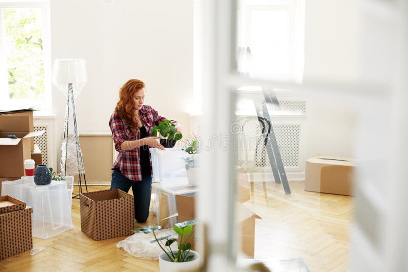 Instalaciones de envasado de la mujer en las cajas durante la relocalización a la nueva casa foto de archivo libre de regalías Instalaciones de envasado de la mujer en las cajas durante la relocalización a la nueva casa foto de archivo libre de regalías
