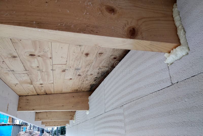 Instalación de vigas de madera de techo con espuma de pulverización en una pared de la casa en construcción imágenes de archivo libres de regalías Instalación de vigas de madera de techo con espuma de pulverización en una pared de la casa en construcción imágenes de archivo libres de regalías