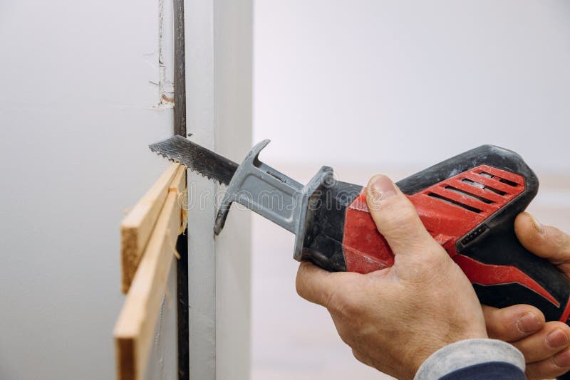 Installing a wooden beam cased opening walkway between rooms, closeup hand of woodworker with cutting tool hackzall cut wooden plank manual labor. Installing a wooden beam cased opening walkway between rooms, closeup hand of woodworker with cutting tool hackzall cut wooden plank manual labor