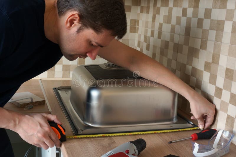 Installation d'évier de cuisine d'acier inoxydable par l'homme Rénovation de la cuisine image libre de droits Installation d'évier de cuisine d'acier inoxydable par l'homme Rénovation de la cuisine image libre de droits