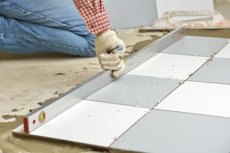 Installation des carreaux de céramique sur un étage image stock Installation des carreaux de céramique sur un étage image stock