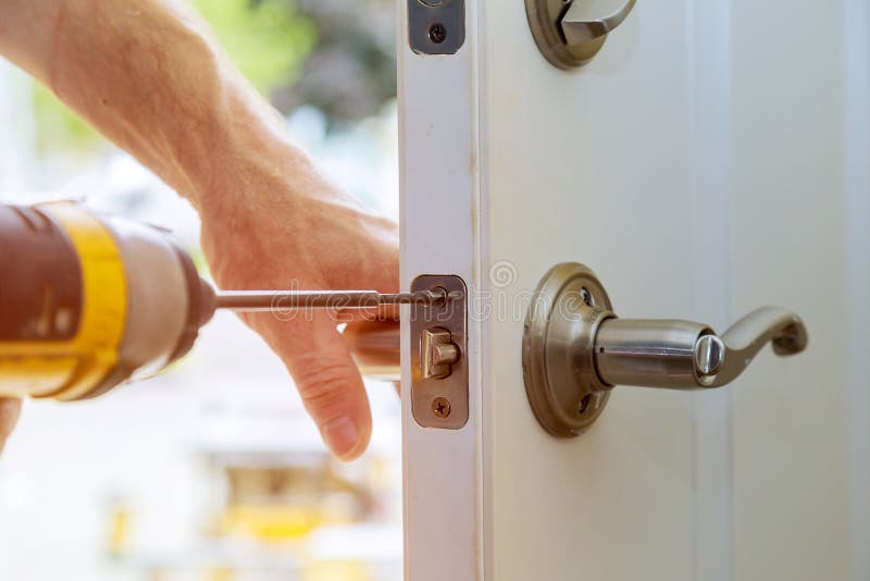 Installation locked interior door knobs, close-up woodworker hands install lock. royalty free stock image