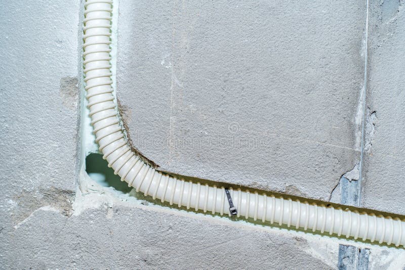 Installation of electrical wiring in a concrete wall using a corrugated pipe for safe wiring. Close-up. Installation of electrical wiring in a concrete wall using a corrugated pipe for safe wiring. Close-up