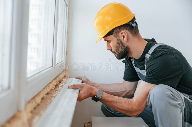 Installazione di un davanzale. l'uomo sta riparando nell'appartamento.