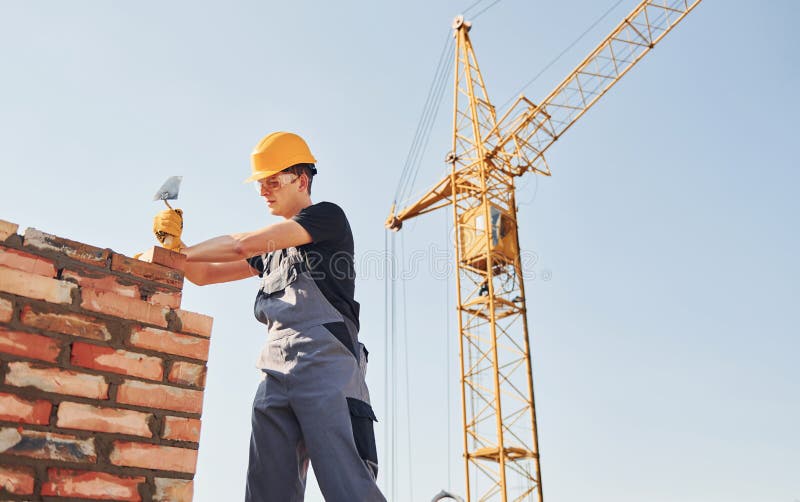 Installing Brick Wall. Construction Worker in Uniform and Safety