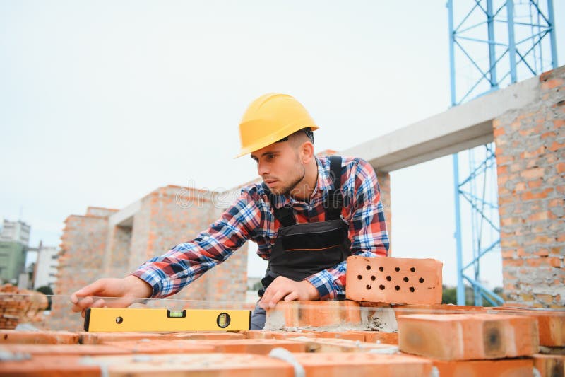 Installing Brick Wall. Construction Worker in Uniform and Safety Equipment Have Job on Building
