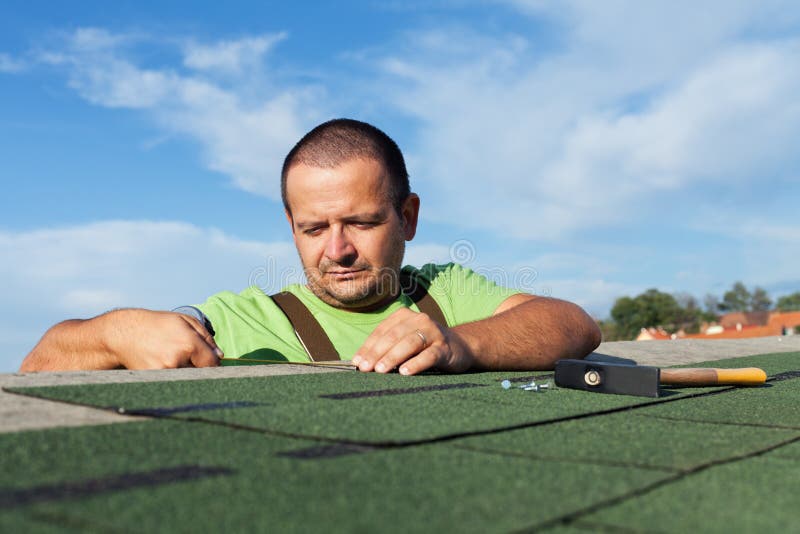 Installing the last strip of bitumen roof shingles stock image