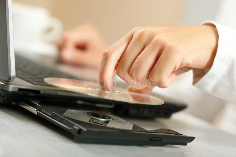Installing software. Woman's hand insert CD in laptop Installing software. Woman's hand insert CD in laptop