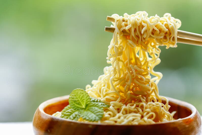 Instant noodle in wooden bowl with bamboo chopstick on green background stock photos Instant noodle in wooden bowl with bamboo chopstick on green background stock photos