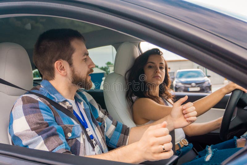 Instructor masculin de predare pentru a conduce o femeie în timpul lecției de conducere Lady ascultare cu atenție. Cursuri de cond stock photography