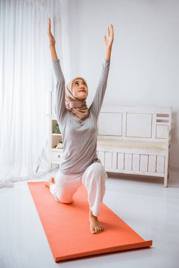 Instructora musulmana con hijab enseñando yoga anjaneyasana posando sobre colchón fotos de archivo