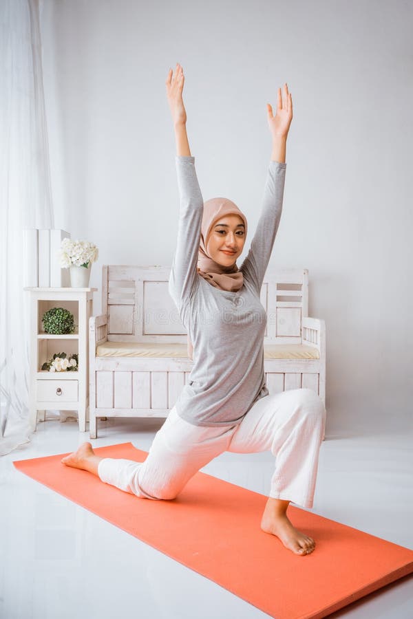 Instructora musulmana sonriente usando hijab anjaneyasana yoga posar pilates en colchón imagenes de archivo