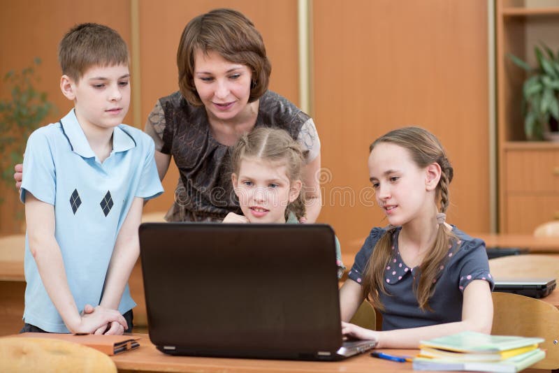 Instruisez les enfants et le professeur à l'ordinateur portable dans la salle de classe photo stock Instruisez les enfants et le professeur à l'ordinateur portable dans la salle de classe photo stock