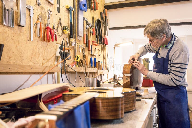Instrument maker repairing an old acoustic guitar royalty free stock photography Instrument maker repairing an old acoustic guitar royalty free stock photography