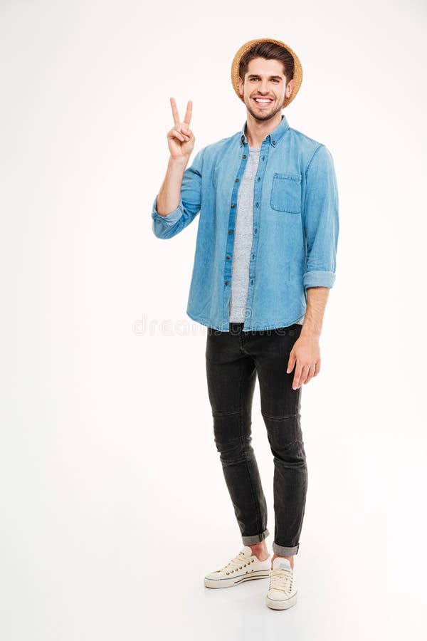 Full length of smiling young man standing and showing peace sign over white background. Full length of smiling young man standing and showing peace sign over white background