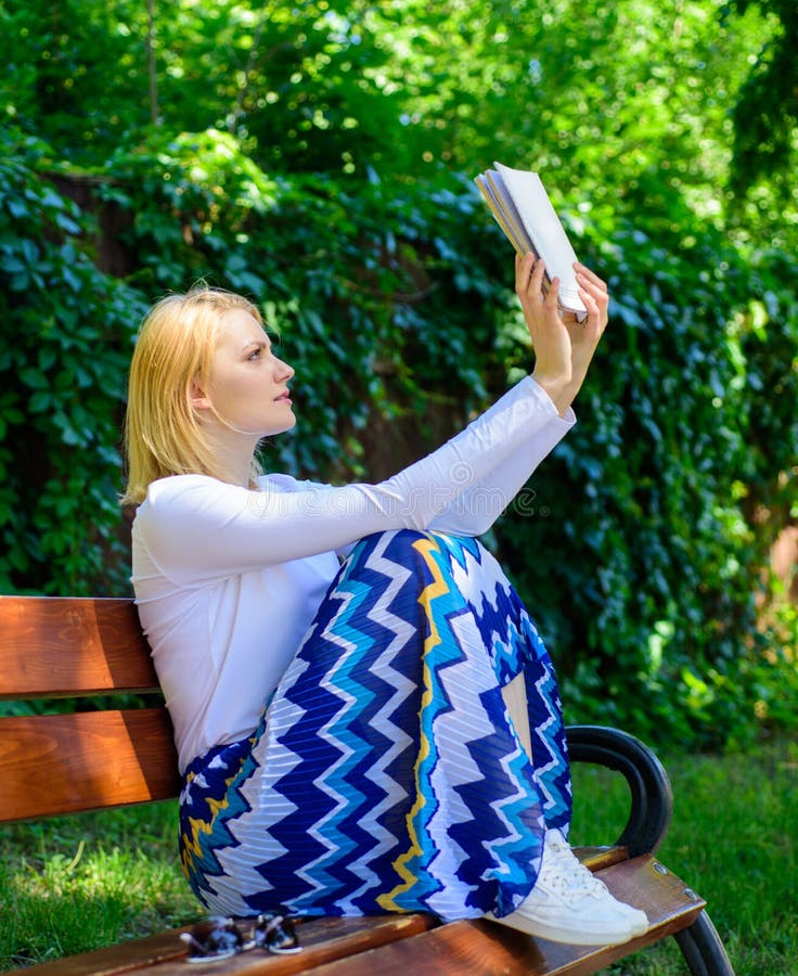 Intellektuell hobby Flickan sitter bänken som kopplar av med boken, grön naturbakgrund Bok för nätt bokmal för dam upptagen läst arkivfoton Intellektuell hobby Flickan sitter bänken som kopplar av med boken, grön naturbakgrund Bok för nätt bokmal för dam upptagen läst arkivfoton