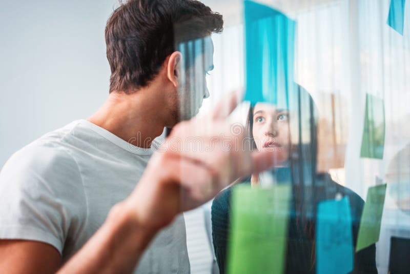 Intelligent coworkers people brainstorming new business plan posted on a sticky glass note wall royalty free stock image Intelligent coworkers people brainstorming new business plan posted on a sticky glass note wall royalty free stock image