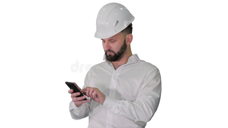 Intelligenter Ingenieur im weißen Hemd und Sicherheitstechnikhut mithilfe des Smartphone auf weißem Hintergrund. stock footage