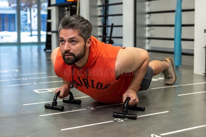 Young fitness woman, stands on push up bars stand, doing plunk