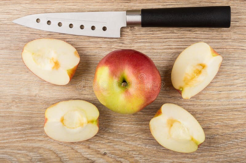 Interi mela e pezzi rossi, coltello da cucina sulla tavola di legno fotografia stock libera da diritti Interi mela e pezzi rossi, coltello da cucina sulla tavola di legno fotografia stock libera da diritti