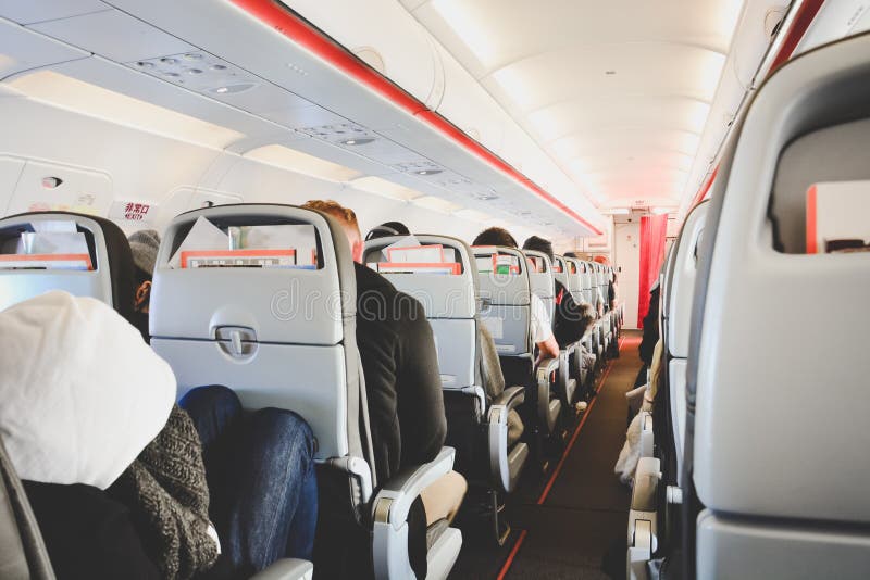 Interior of airplane in economy class with passengers sitting on seats, low cost airline, travel concept royalty free stock image Interior of airplane in economy class with passengers sitting on seats, low cost airline, travel concept royalty free stock image