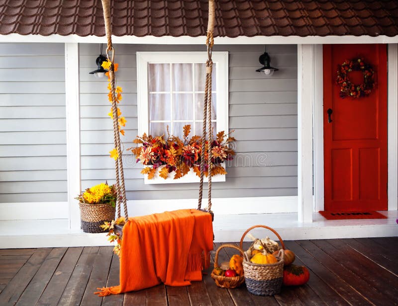 Interior of an autumn patio. swing is adorned with autumn leaves and orange knitted plaid. Basket with pumpkins and autumn vegetab. Les. The window is decorated royalty free stock image
