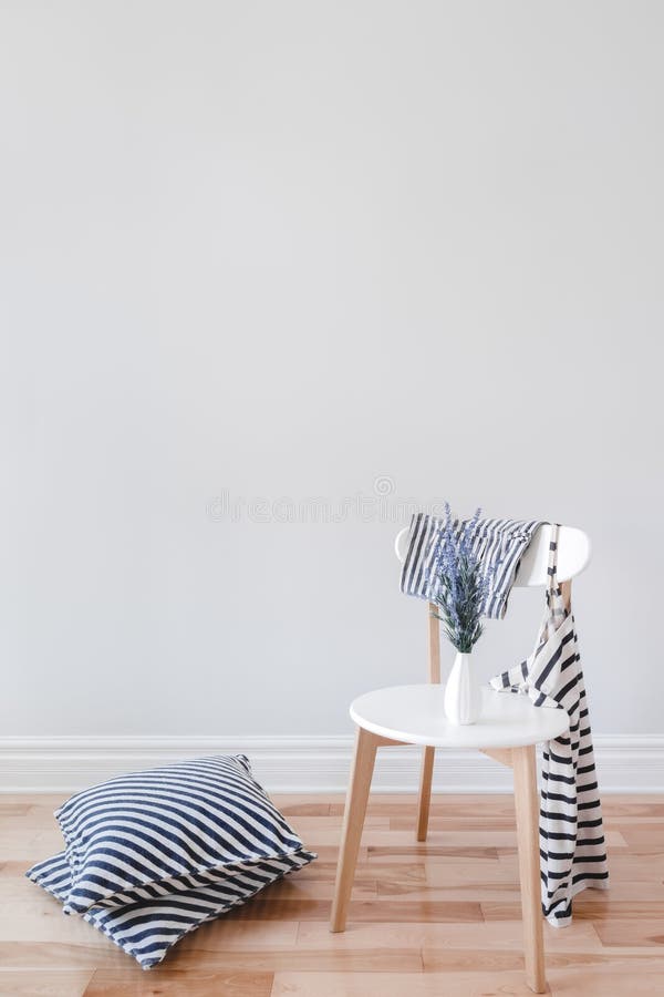 Modern interior with stylish chair, lavender flowers, striped cushions and clothes, on gray wall background with copy space. Modern interior with stylish chair, lavender flowers, striped cushions and clothes, on gray wall background with copy space