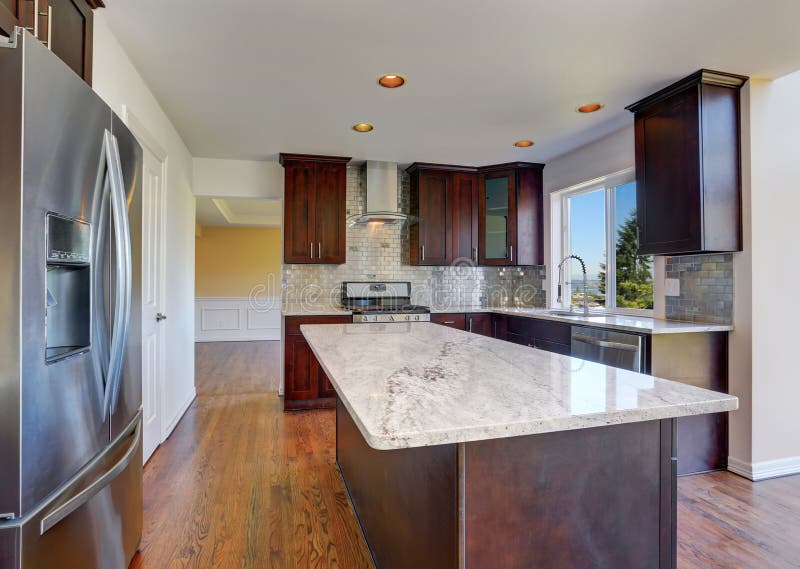 Interior da sala da cozinha com profundamente - os armários marrons com parte superior contrária do granito