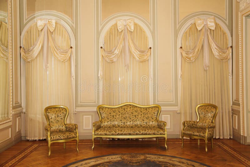 A luxurious room with furniture and curtains on the windows waiting for guests.