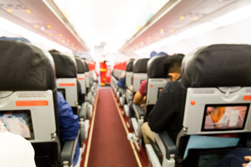 Interior Defocused de la cabina del aeroplano con los asientos y los pasajeros foto de archivo Interior Defocused de la cabina del aeroplano con los asientos y los pasajeros foto de archivo