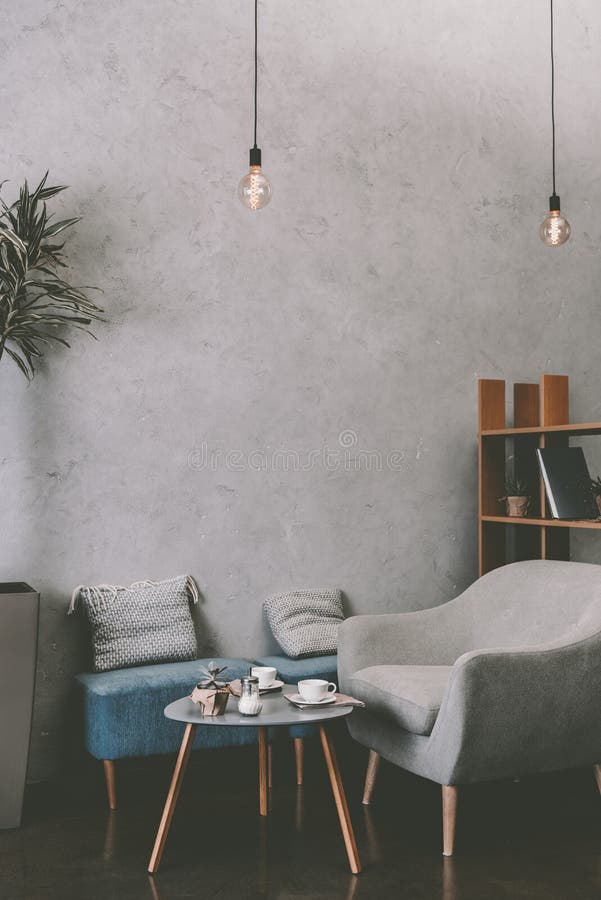 Interior del café acogedor moderno con las bombillas de la butaca, de la tabla y del vintage imagen de archivo libre de regalías Interior del café acogedor moderno con las bombillas de la butaca, de la tabla y del vintage imagen de archivo libre de regalías