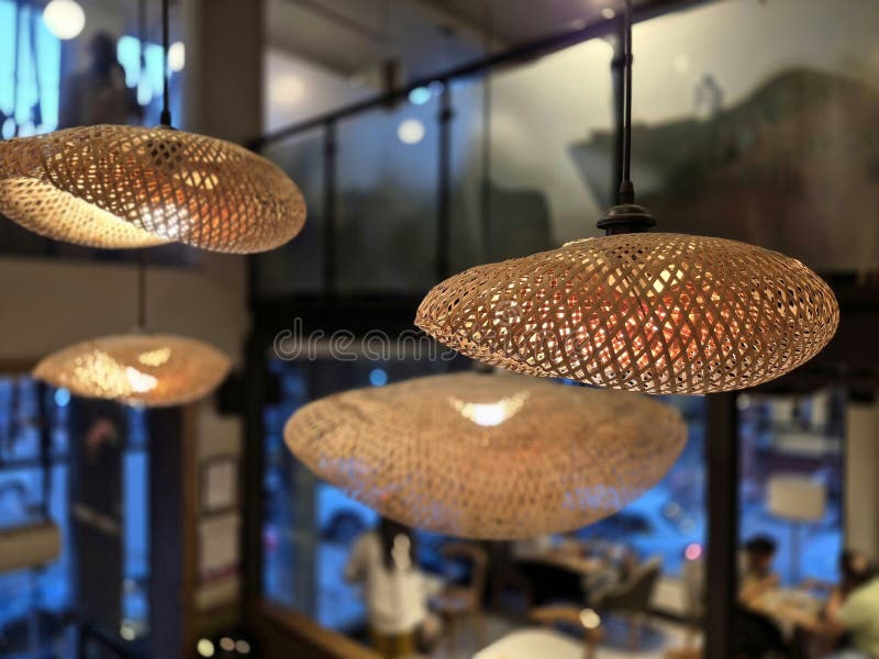 Interior design wicker pendant ceiling light shade. moody image of a tropical style natural cane lighshade over a electric light stock images