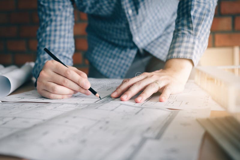 Interior designer or architect reviewing blueprints and holding stock photography