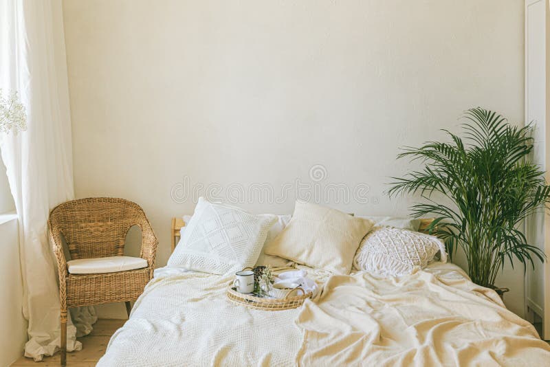 Modern romantic scandi boho style bedroom interior with decorative pillows, green plant and empty wall for poster or art mock-ups. Light warm cozy comfortable home. Modern romantic scandi boho style bedroom interior with decorative pillows, green plant and empty wall for poster or art mock-ups. Light warm cozy comfortable home