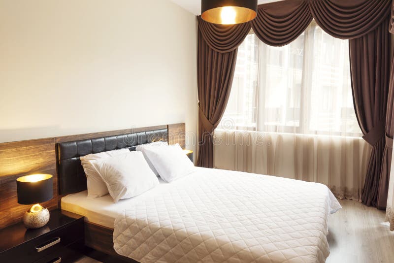 Interior of modern bedroom with cozy double bed. Windows with long curtains, drapery and sheers. Interior photography royalty free stock photos Interior of modern bedroom with cozy double bed. Windows with long curtains, drapery and sheers. Interior photography royalty free stock photos