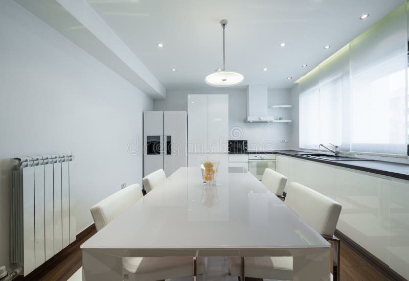 Interior of a Modern Luxury Bright White Kitchen with Dining Tab Stock